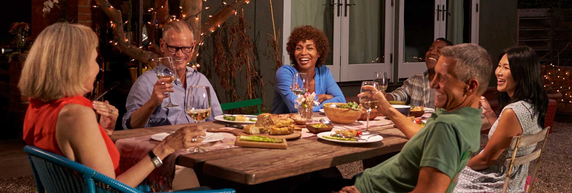 A group of friends enjoying dinner outside in their backyard